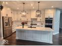 Modern kitchen with white cabinets, a large island with quartz countertops and stainless steel appliances at 15873 Hush Hickory Bnd, Westfield, IN 46074