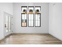 Bright, empty room with wood-look flooring, three large windows and modern light fixture at 1677 Solebar Way, Westfield, IN 46074