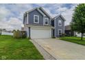 Two-story home with blue siding, a white garage door, driveway, and green lawn with a small tree at 2485 Bristol Dr, Franklin, IN 46131