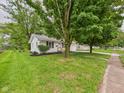 Cozy one-story house with a green lawn and mature trees surrounding the property at 308 Mohawk St, Anderson, IN 46012