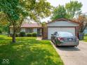 Quaint single-story home with a brick facade, lush green lawn, mature trees, and an attached two-car garage at 3303 Wedgewood Dr, Indianapolis, IN 46227