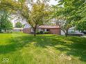 A well-maintained single-story home featuring a lush lawn, mature trees, and an attached two-car garage at 3303 Wedgewood Dr, Indianapolis, IN 46227