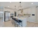 Modern kitchen with stainless steel appliances, sleek white cabinets, quartz countertops and large central island with bar stools at 4163 Ironclad Dr, Bargersville, IN 46106