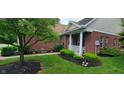 Charming front of brick house with trimmed bushes, mulch bed and covered porch area at 5189 Bally Bunion Dr, Avon, IN 46123