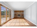 Bright living room featuring hardwood floors, a brick fireplace, and sliding glass doors to the deck at 567 Hawthorne Dr, Carmel, IN 46033