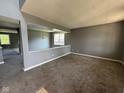 Open-concept living room with modern gray carpet and walls, bathed in natural light with a chandelier at 5683 James Blair Dr, Indianapolis, IN 46234