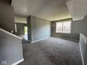 A spacious living room with soft gray carpet, neutral gray walls and natural light from the window at 5683 James Blair Dr, Indianapolis, IN 46234
