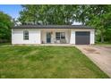 Inviting single-story home with a gray garage door, front lawn, and charming porch with seating at 5811 Simmul Cir, Indianapolis, IN 46221