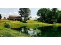 Scenic view of pond reflecting lush landscape with mature trees, with home in distance and greenhouse at 600 Old Moore Rd, Martinsville, IN 46151