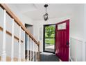 Bright entryway featuring a staircase, modern light fixture, and a stylish front door at 6146 Rucker Rd, Indianapolis, IN 46220