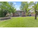 Quaint red brick home with a manicured lawn and lush trees in a suburban neighborhood at 6477 N Park Ave, Indianapolis, IN 46220