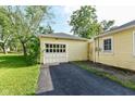 A detached yellow garage with white doors and a black driveway at 713 W Cromer Ave, Muncie, IN 47303