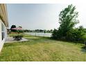 Backyard overlooking a serene pond, featuring a patio, green lawn, and mature trees at 8148 Gathering Cir, Indianapolis, IN 46259