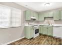 Bright kitchen with modern appliances, light green cabinets, and wood-style flooring at 8720 Yardley Ct # 108, Indianapolis, IN 46268