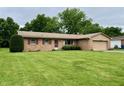 Charming single-story home featuring brick facade, attached garage, and well-manicured front lawn at 902 N Bauman St, Indianapolis, IN 46214