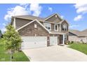 A two-story home with a brick and siding exterior, featuring a three-car garage and a well-maintained green lawn at 928 Ridge Rock Ln, Bargersville, IN 46106