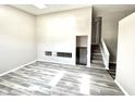 Bright living room featuring sleek, wood-look flooring, neutral paint, and an open staircase at 10922 Snowdrop Way, Indianapolis, IN 46235