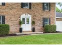 Close-up of the brick home featuring a white double-door entry with black accents and green lawn at 1127 Junco Dr, Columbus, IN 47203