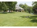 Home exterior featuring a pond view, well-kept lawn, mature trees and shrubbery at 1739 S County Road 450 E, Avon, IN 46123