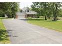View of the home and surrounding landscaping featuring mature trees, a large driveway and green lawn at 1739 S County Road 450 E, Avon, IN 46123