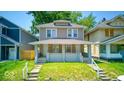 Quaint two-story home featuring a cozy front porch and beautiful green lawn at 420 Eastern Ave, Indianapolis, IN 46201