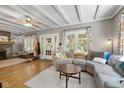 Open living room features hardwood floors, gray sectional sofa, and view of exposed brick fireplace at 552 Woodruff Pl W Dr, Indianapolis, IN 46201
