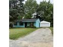 Charming blue home with a gravel driveway and detached two-car garage nestled amongst mature trees at 5938 Price Ln, Indianapolis, IN 46254