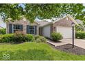 Charming single-story brick home featuring an attached two car garage, a manicured lawn and mature trees at 5967 Peregrine Blvd, Indianapolis, IN 46228
