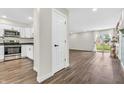 Open living space with wood flooring, white door, kitchen view, and sliding glass doors to the backyard at 6853 Kellum Dr, Indianapolis, IN 46221