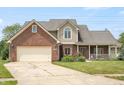 Charming two-story brick home with a covered porch, beautiful lawn, and manicured garden at 7082 Hunters Ridge Dr, Plainfield, IN 46168