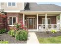 Inviting covered front porch with decorative glass door and manicured flower beds at 7082 Hunters Ridge Dr, Plainfield, IN 46168