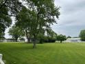 Large green yard with mature trees, white fencing, and partial view of the home at 7195 W 700 N, Fairland, IN 46126