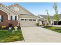 A well-lit two-car garage with a spacious driveway and neat landscaping at 11429 Lottie Cir, Noblesville, IN 46060