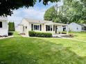 Single story home with green lawn, small bushes, covered entryway, and black shutters at 128 E 36Th St, Anderson, IN 46013