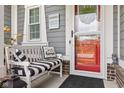 A charming front porch features a white bench with cushions, a decorative owl, and a red door with glass pane at 1505 Avondale Dr, Westfield, IN 46074
