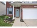 Close-up of the brick-facade home featuring a blue front door, brick surround, and flower bed at 2101 Shadow Fox Dr, Columbus, IN 47201