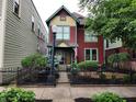 Attractive two-story home with a black iron fence, lush greenery and an American flag at 239 E 11Th St, Indianapolis, IN 46202