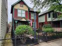 Beautiful red and green two-story home with a well-kept lawn and street light at 239 E 11Th St, Indianapolis, IN 46202