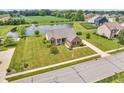 A stunning aerial view showcasing the beautiful home with a pond, pool, and well-maintained lawn at 2948 Chalbury Dr, Plainfield, IN 46168