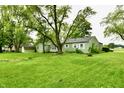 Spacious backyard with a green lawn and mature trees surrounding the property at 415 N 3Rd St, Elwood, IN 46036