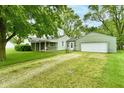 View of the house with attached garage and large front yard with mature trees providing shade at 415 N 3Rd St, Elwood, IN 46036