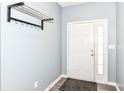Clean entryway featuring light gray walls, gray laminate flooring, coat rack and a white front door with side window at 5439 Maywood Dr, Whitestown, IN 46075