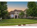 Beautifully landscaped home featuring a well-manicured lawn and mature trees at sunset at 10471 Winghaven Dr, Noblesville, IN 46060