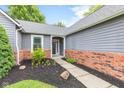 Inviting front entrance with landscaped flower bed and stylish front door, brick, and light gray siding at 11218 Baycreek Dr, Indianapolis, IN 46236
