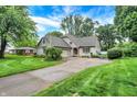 Inviting home showcases manicured landscaping, a circular driveway, and charming architectural details at 116 Bennington Rd, Indianapolis, IN 46227