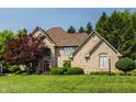 Stunning brick house with lush green lawn, mature trees, and a grand facade at 1229 Helford Ln, Carmel, IN 46032