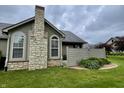 The home features a stone chimney, well-maintained lawn, and neutral colored siding at 125 Bridgemor Ln, Mooresville, IN 46158