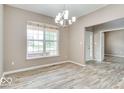 Bright dining room with wood floors, a modern chandelier, and a large window at 12679 Chargers Ct, Fishers, IN 46037