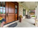 Inviting front porch with seating area, decorative planters and a stained wood door at 13346 W Sherbern Dr, Carmel, IN 46032