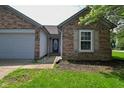 Brick house with a front door, green grass and an attached two-car garage at 1411 Mimosa Ct, Greenfield, IN 46140
